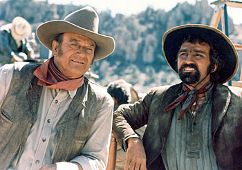 John Wayne and Pedro Armendariz Jr. take a break from filming 
“The Undefeated” (‘69 20th Century Fox). 