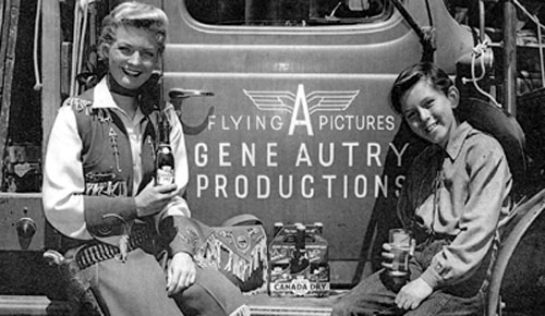 Gail Davis as Annie Oakley and Jimmy Hawkins as her kid brother Tagg pause beside a Gene Autry Flying A equipment truck in 1953 to enjoy some Canada Dry. (Photo courtesy Jimmy Hawkins.)