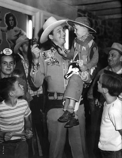 Monte Hale entertains a group of young fans at a theatre in 1946. (Note the poster of Jane Russell in "The Outlaw" behind Monte.) (Photo courtesy Mrs. Joanne Hale and The Autry National Center.)